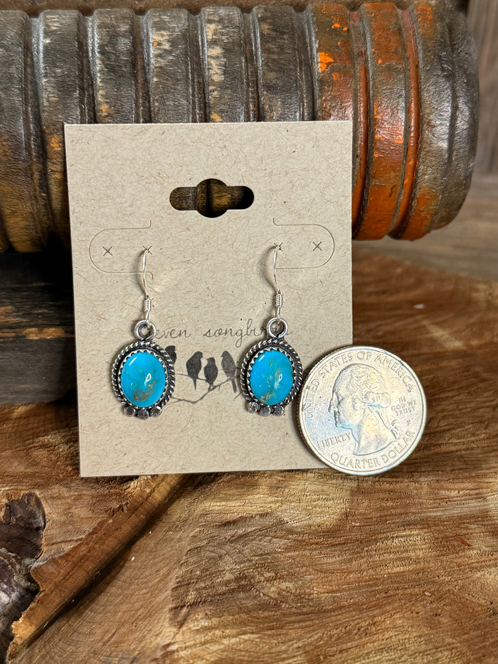 Turquoise oval fishhook earrings with silver beaded bezel, dangling view