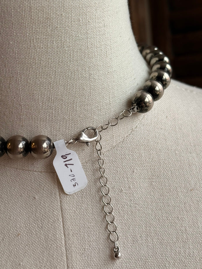 Graduated silver pearl necklace close-up, silver beads with heart-shaped clasp charm