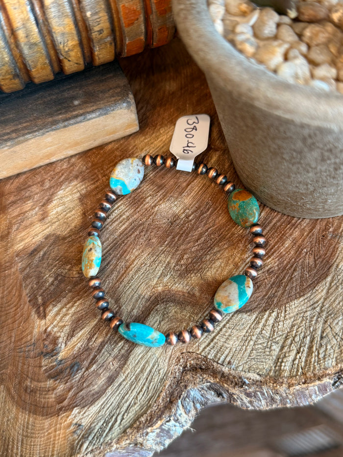 Copper stretchy bracelet with oval turquoise stones and dark metal bead spacers.