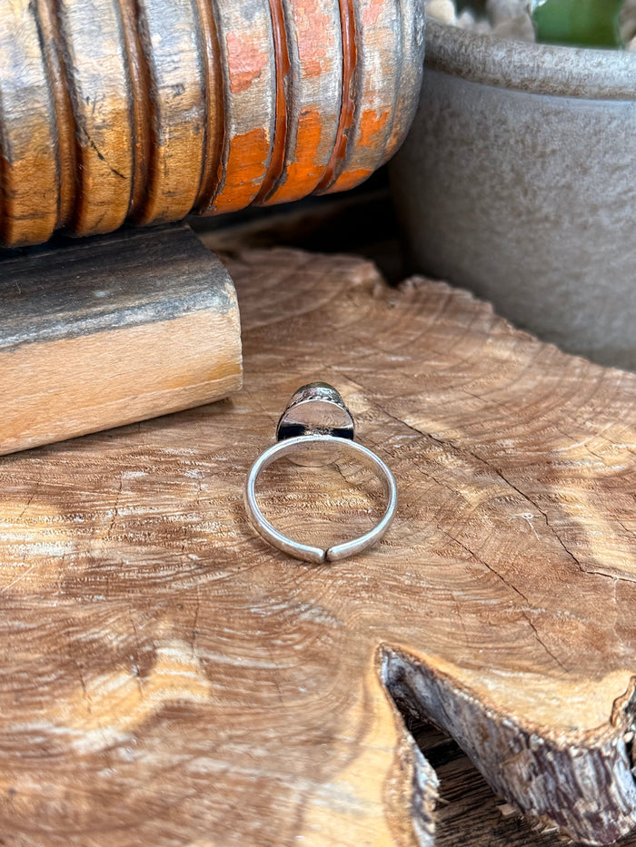 Silver-plated adjustable ring open band with small prongs holding blue oval stone