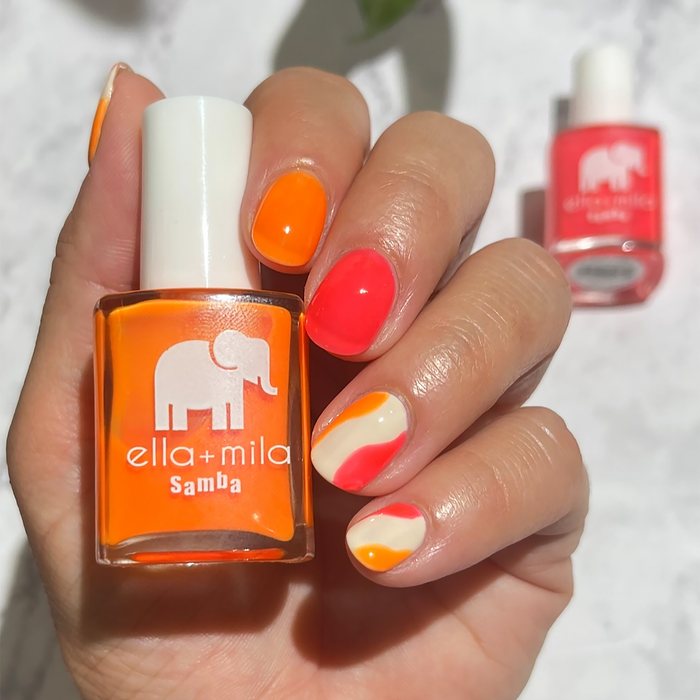 Aperol Spritz orange with coral and white swirl accent nails, holding the bottle