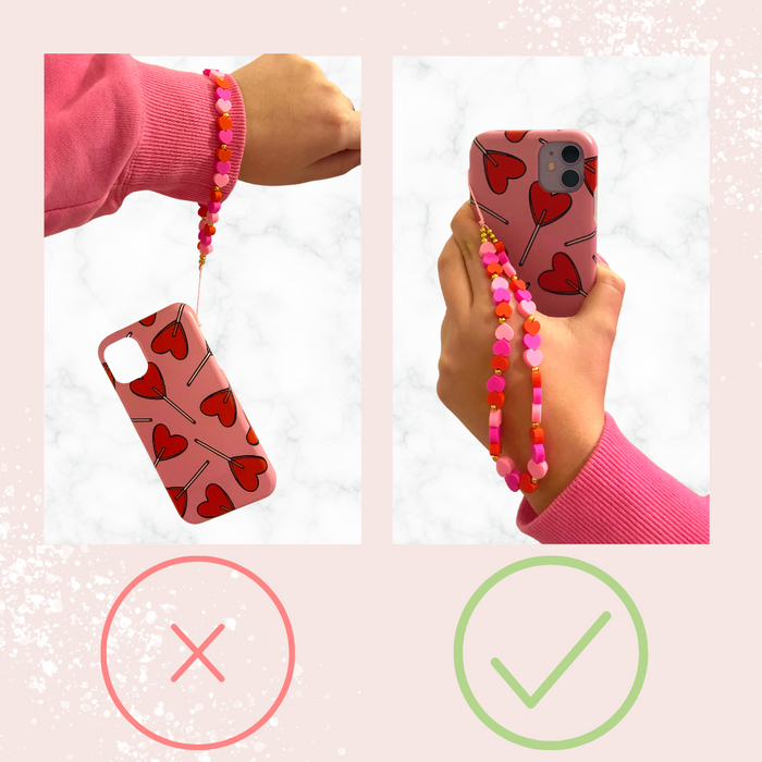 Hand holding heart-shaped phone case with holographic butterfly beaded phone strap; one shown correctly, one incorrectly.
