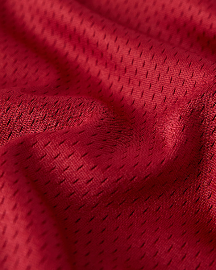 Deep red mesh fabric with small perforated holes throughout, showing texture and weave detail.