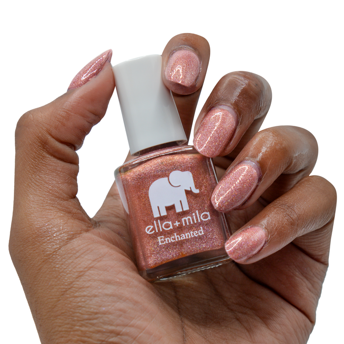 Oasis holographic red orange nail polish on a deep skin tone, hand holding the bottle