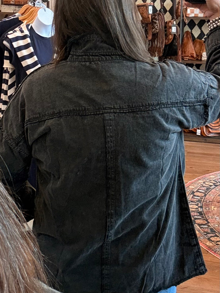 Black denim jacket back with studded yoke and buttoned pockets