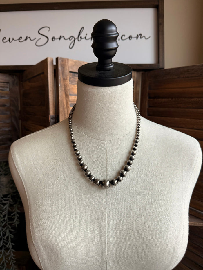 Graduated silver pearl bead necklace on mannequin, rounded bead strand