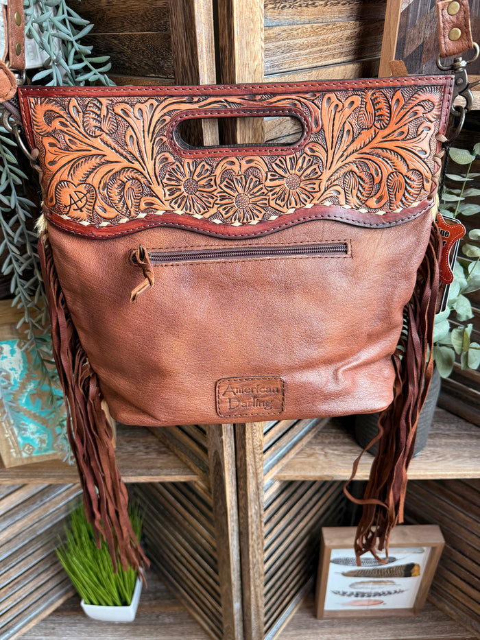 Brown leather crossbody purse with floral tooled top, fringed sides, and adjustable strap