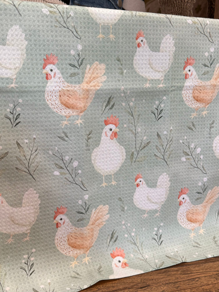 Light sage towel close-up with white hens, orange roosters, and gray leaves