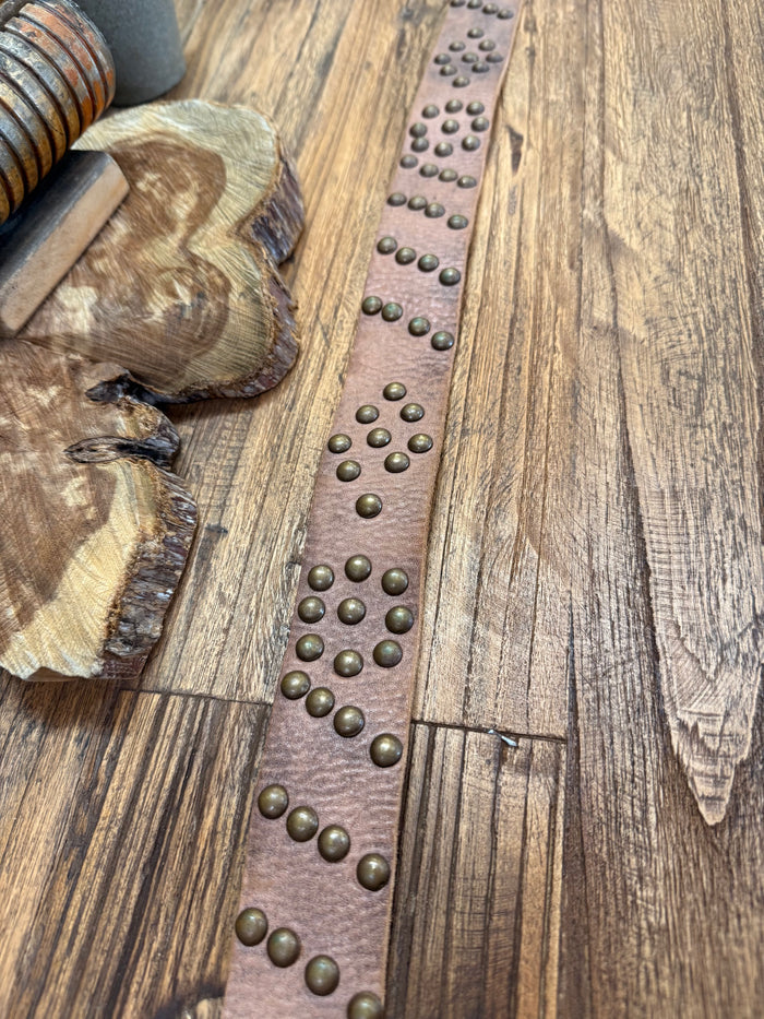 Brown leather strap detail with long row of round brass studs