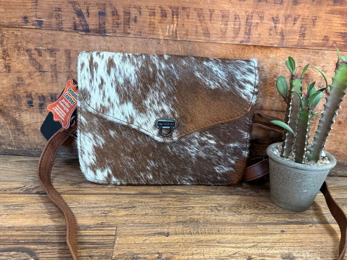 Mini flap crossbody purse with dark-and-white cowhide pattern and metal buckle clasp