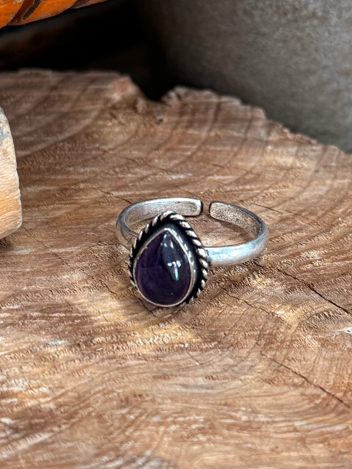 Silver-tone adjustable ring with deep purple oval cabochon stone top view