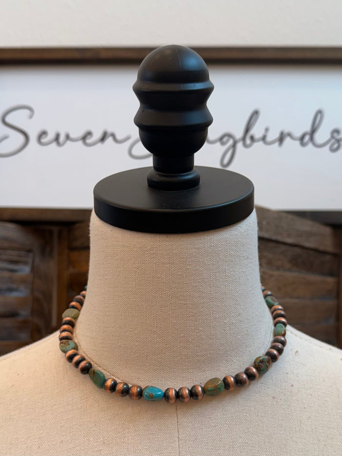 Turquoise and copper bead necklace laid flat on a mannequin