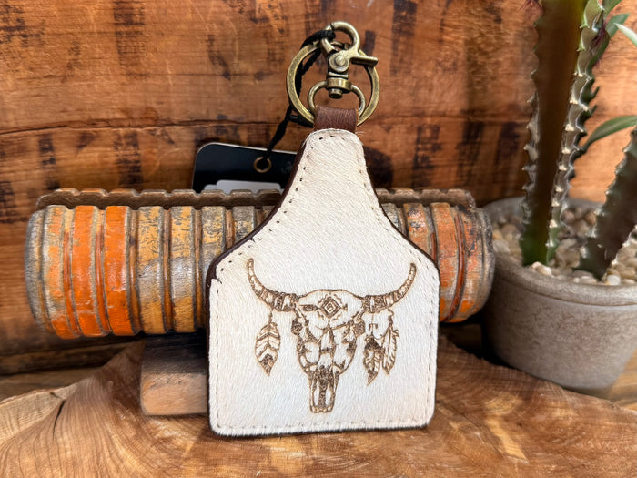 Cow skull hair-on key fob with curved white patch and gold-tone bull skull graphic
