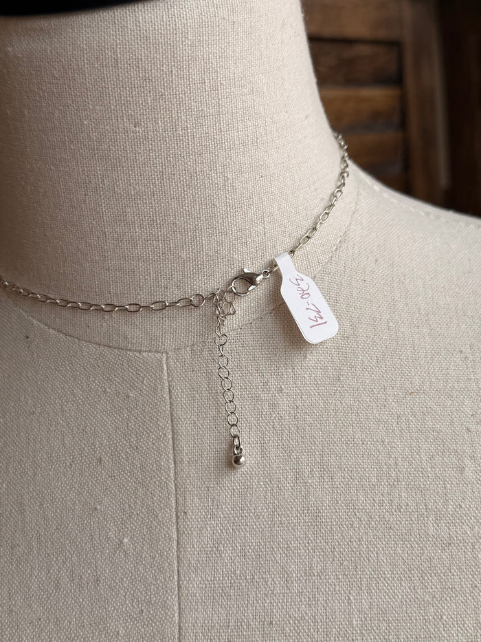 Silver chain necklace with small white tag at the back of the chain