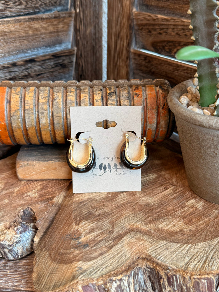 Gold-tone amber teardrop hoop earrings with hinged backs on display card