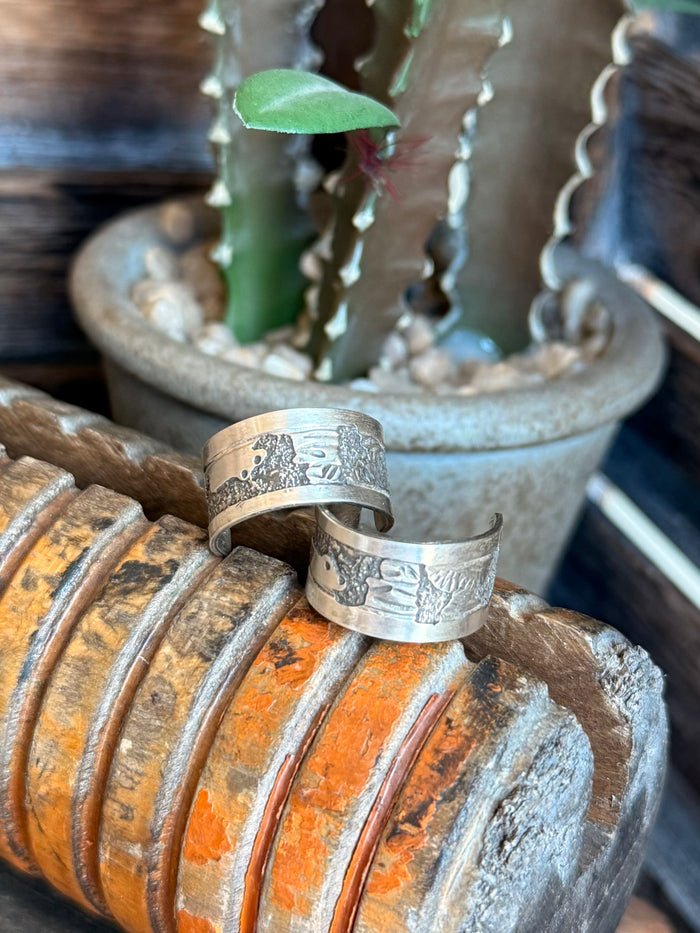 Sterling hoop earrings featuring engraved band motifs on both hoops.