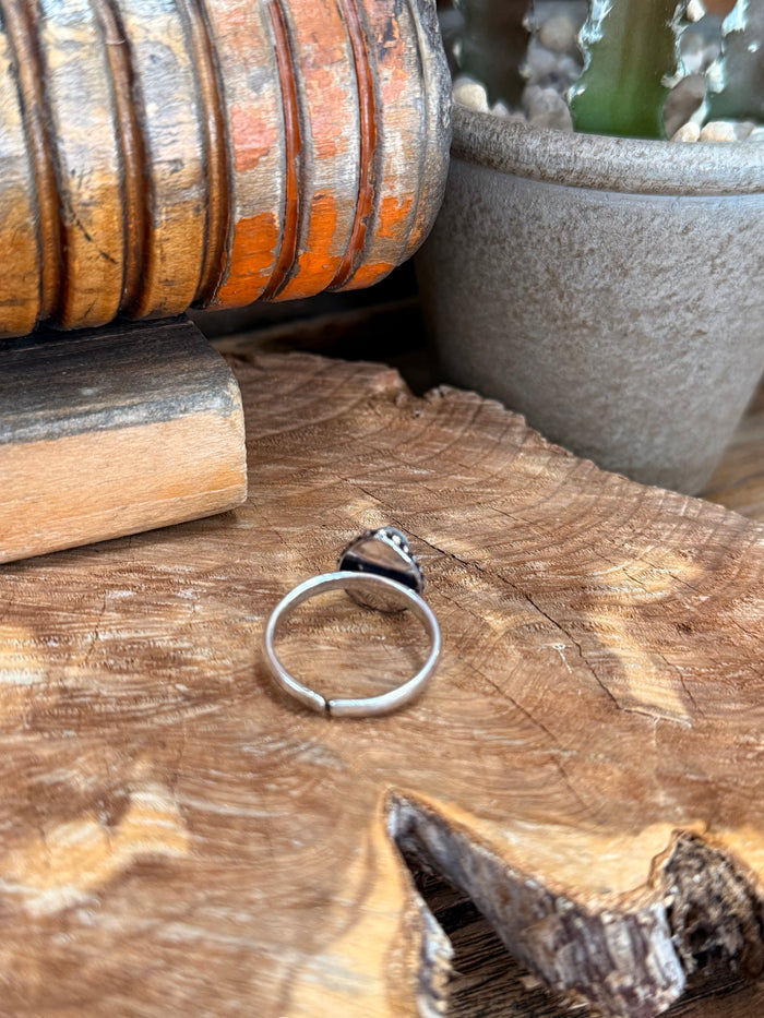 Adjustable silver-tone ring with oval blue stone, side angle view