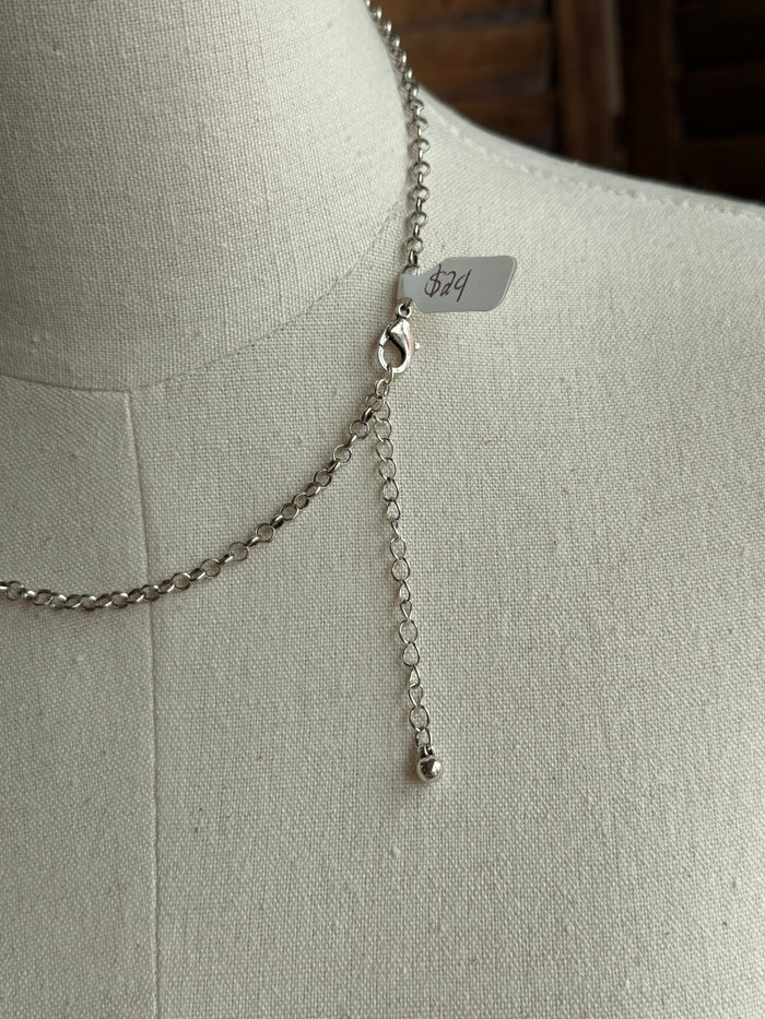 Silver chain necklace with small dangling charm and engraved bar tag