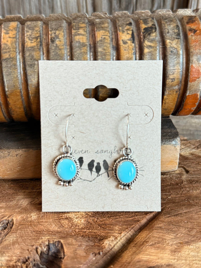 Turquoise round fishhook earrings with ornate silver frames and dangling stones