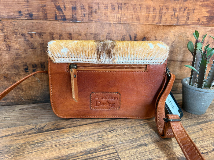 Brown leather crossbody purse with speckled cowhide flap, zipper, and American Darling patch
