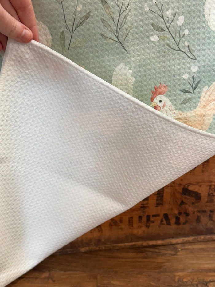 White towel edge showing folded seam with chicken print on sage fabric