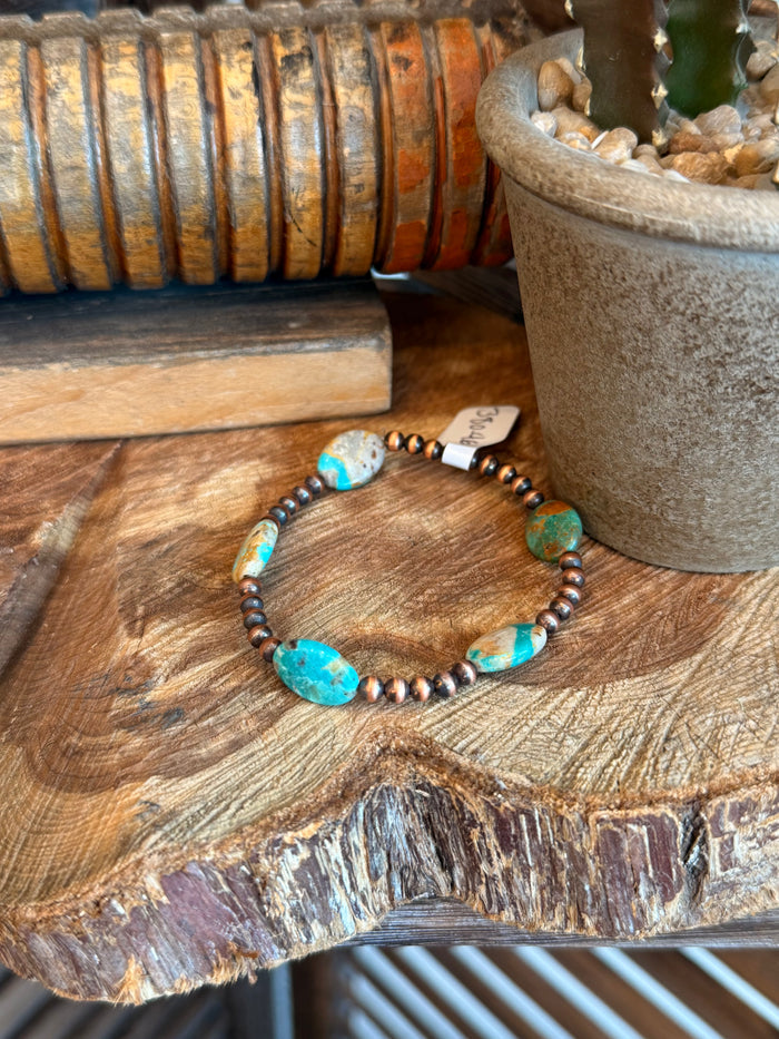 Copper stretchy bracelet with oval turquoise stone beads and dark spacer beads.