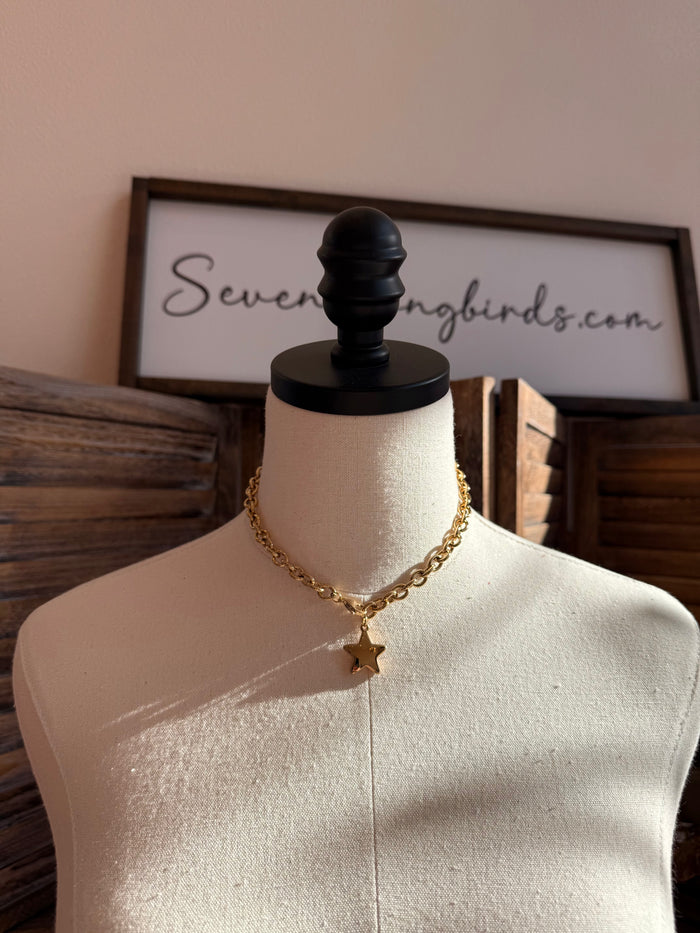 Gold-plated star necklace with small dangling star pendant on a curb chain
