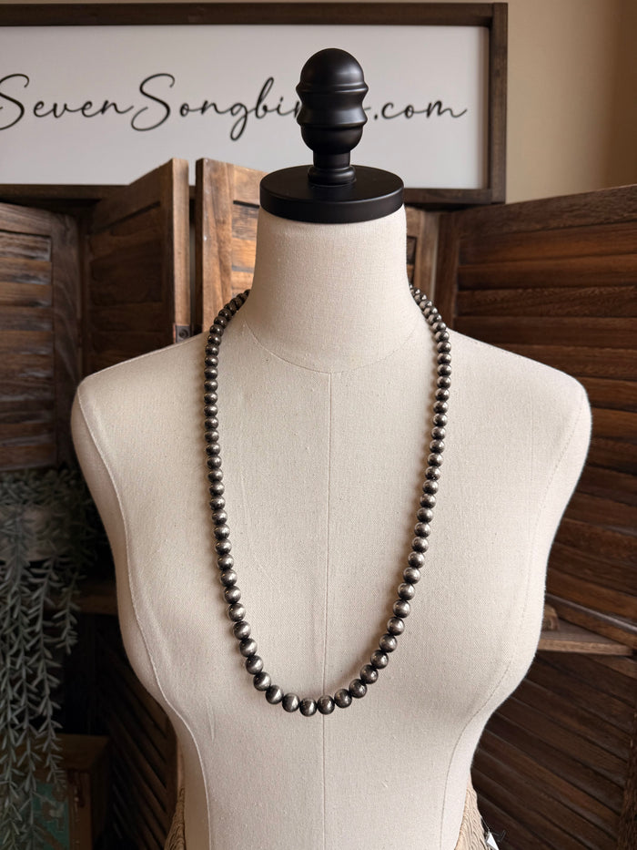 Dark silver metallic pearl bead necklace draped on mannequin