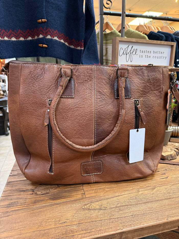 Brown leather tote with top handles, shoulder strap, and hanging tag