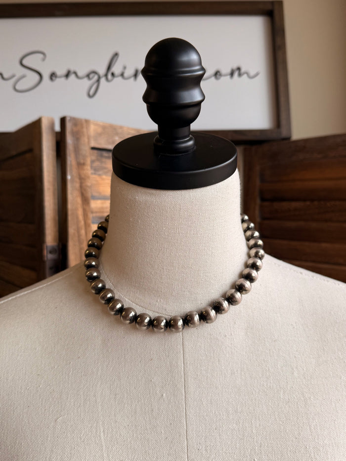 Graduated silver pearl necklace with uniform bead strand and chain tassel