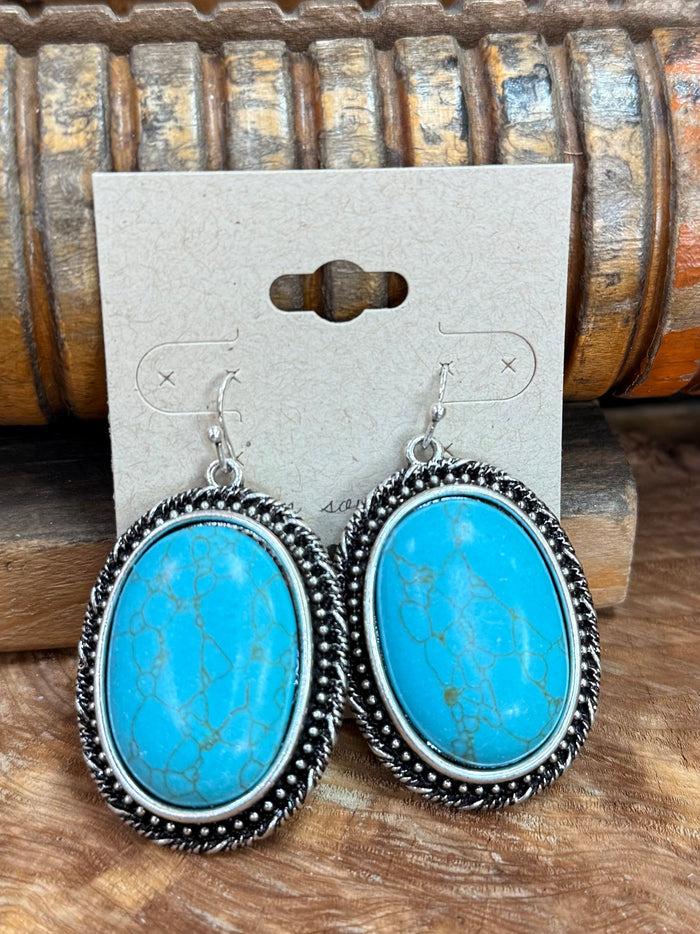 Silver fishhook earrings, close-up of two oval turquoise cabochons with beaded edge