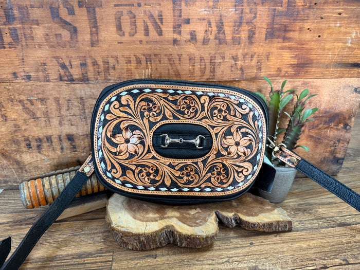 Tooled crossbody purse with oval flap and dark blue strap, ornate floral leather design