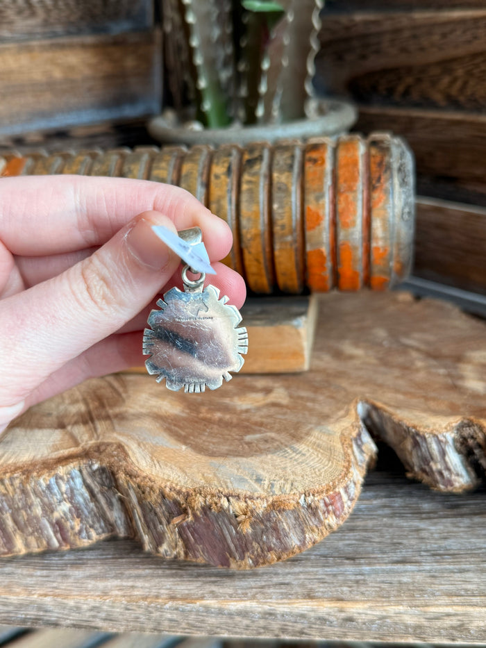 Sterling silver turquoise pendant held in hand, round cabochon with sunburst frame