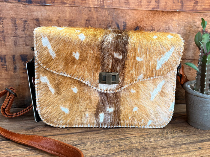Speckled cowhide flap crossbody purse with black square buckle and brown leather strap