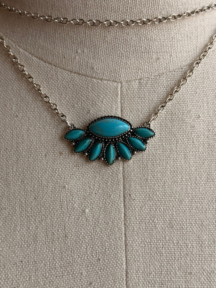 Turquoise fan necklace pendant with blue oval center and petal details on silver chain