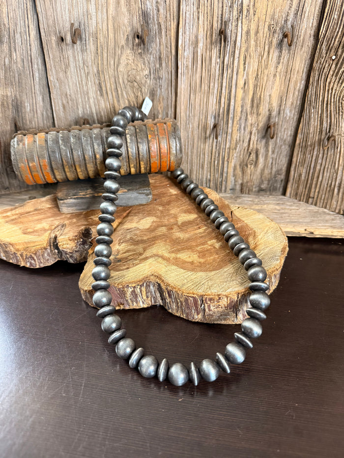 Graduated dark-silver pearl necklace with rounded bead segments and clasp at one end