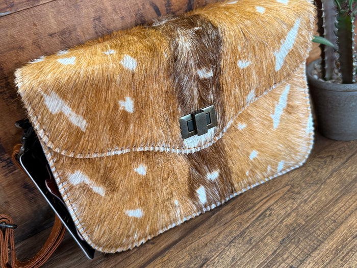 Speckled cowhide flap crossbody purse, angled view, with black buckle and brown strap