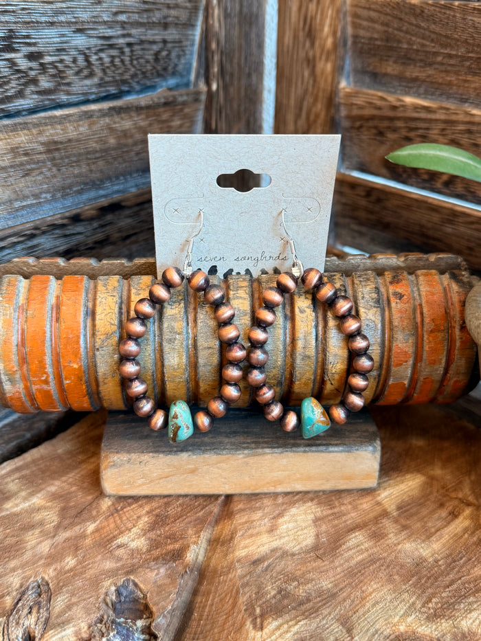 Copper beaded teardrop earrings with turquoise drops on display card
