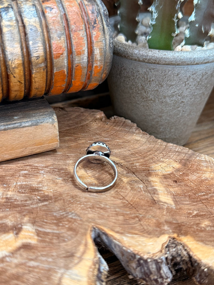 Adjustable silver-tone band ring with purple oval stone set in raised bezel