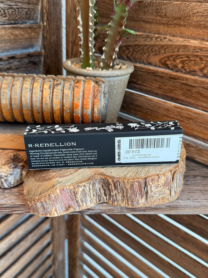 Velvet Desperado roll-on perfume oil box with ingredient text, on wooden ledge