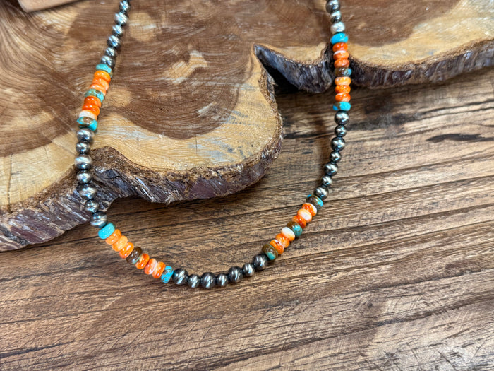Close-up turquoise and orange bead necklace with dark metal bead strand detail