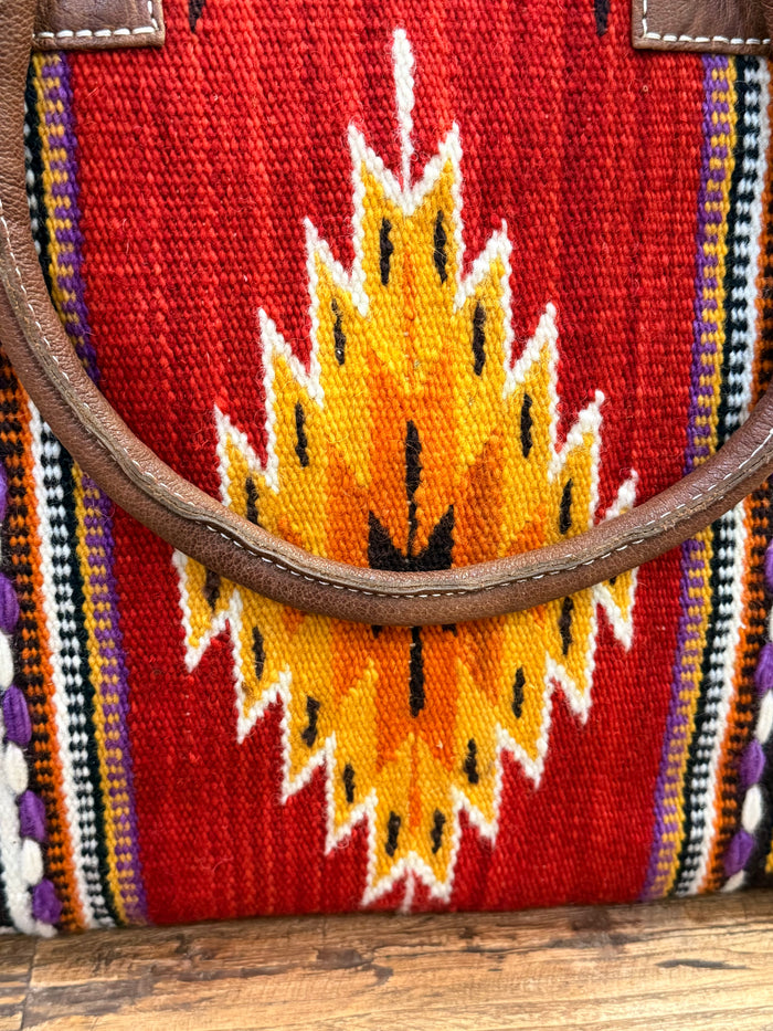 Red woven tote close-up with yellow flame motif and dark leather trim