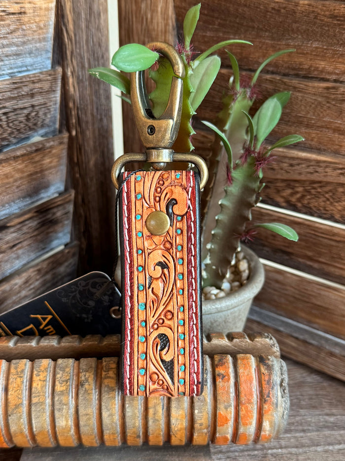 Tooled leather keychain with orange tooled pattern, turquoise trim, and brass clasp ring
