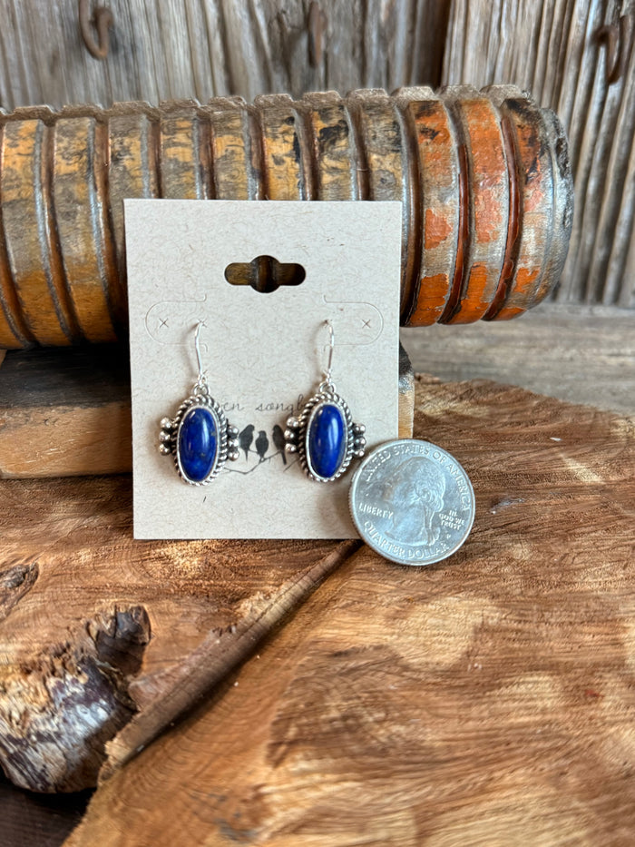 Sterling silver fishhook earrings with blue oval lapis stones beside a coin for scale.