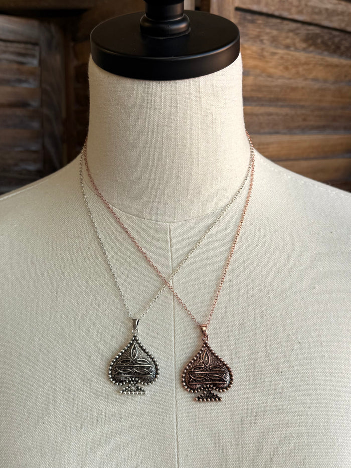 Spade pendant necklaces on mannequin: two chains with copper and silver teardrop pendants