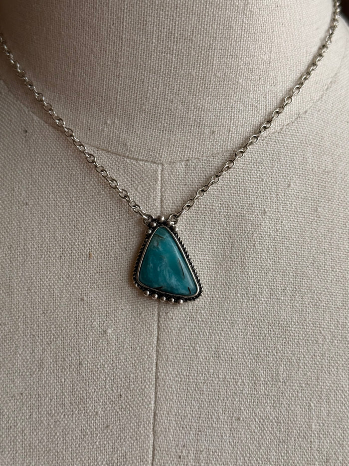 Turquoise triangle pendant with dark border on silver chain