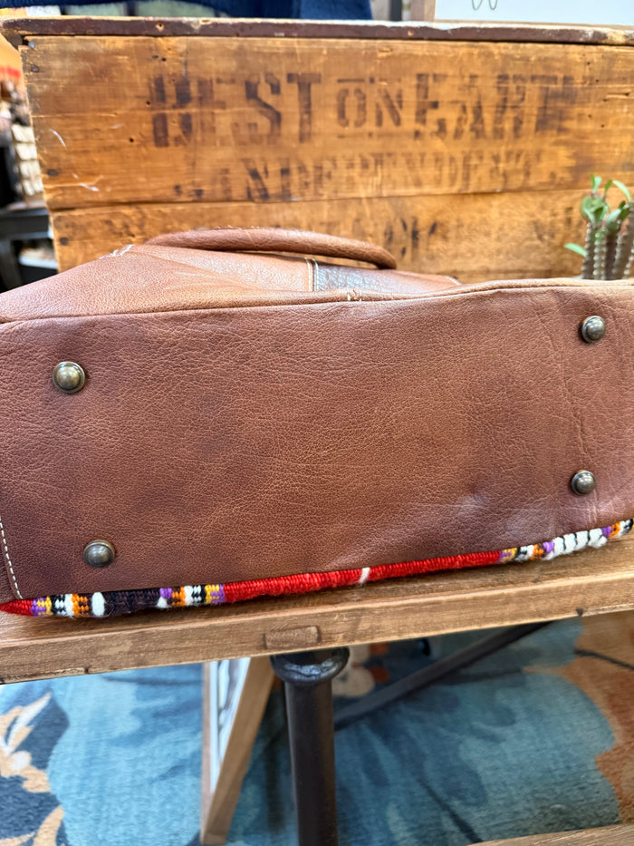 Brown leather tote side panel with metal studs and curved seam detail