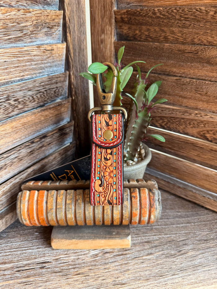 Tooled leather keychain with orange tooling and turquoise edges on leather strap