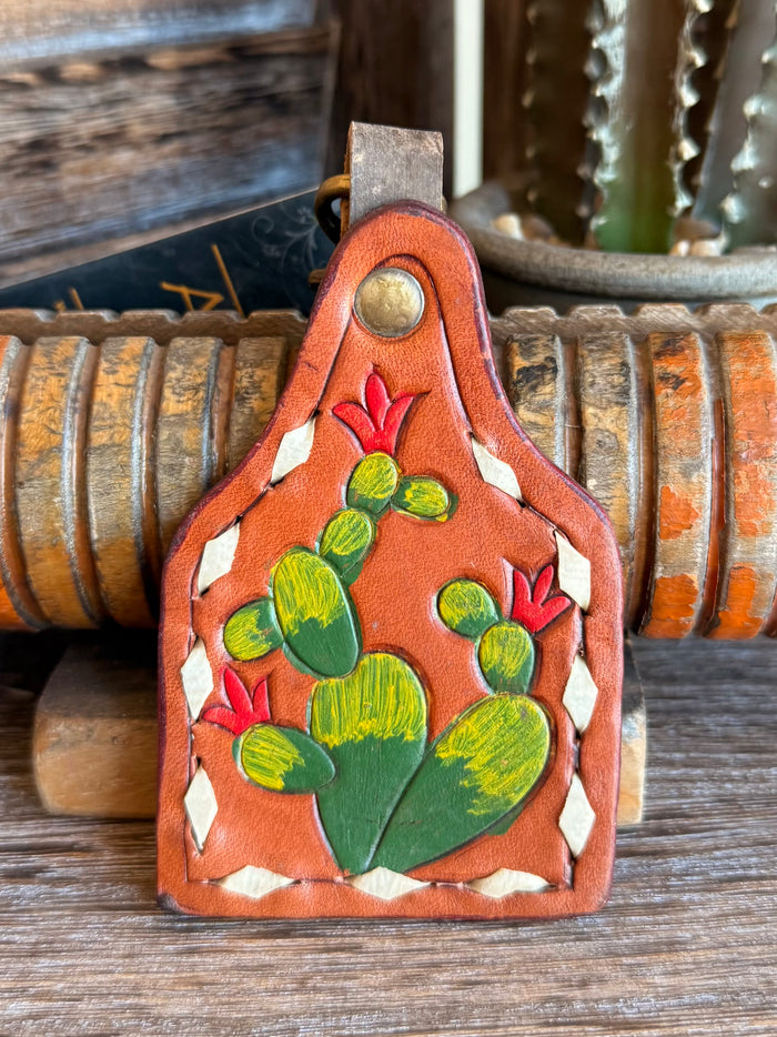 Orange leather cactus keychain with hand-painted green cactus and red blooms.