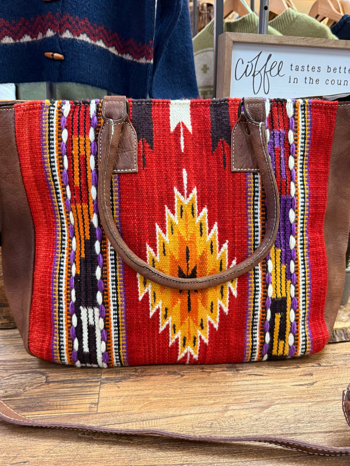 Red woven tote with geometric stripes, dark leather top handles and side straps